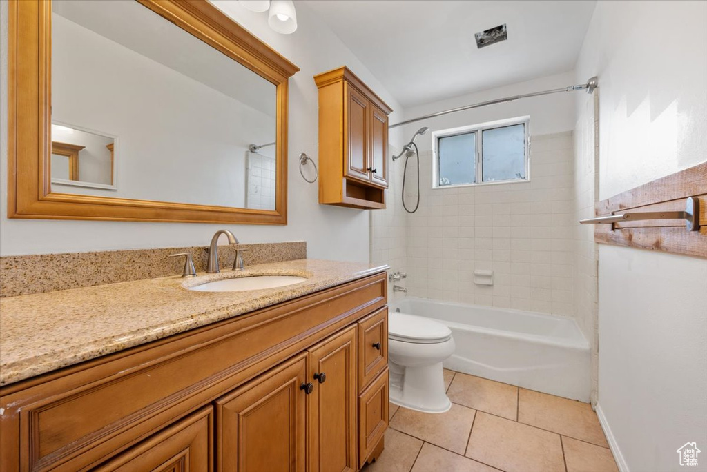 Full bathroom with tiled shower / bath, toilet, tile flooring, and vanity
