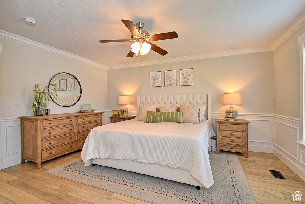 Bedroom featuring ceiling fan, crown molding, and light wood-type flooring