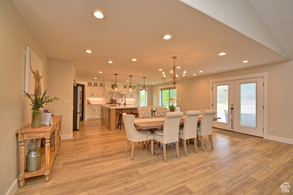 Dining space with french doors, light hardwood / wood-style flooring, sink, and a chandelier