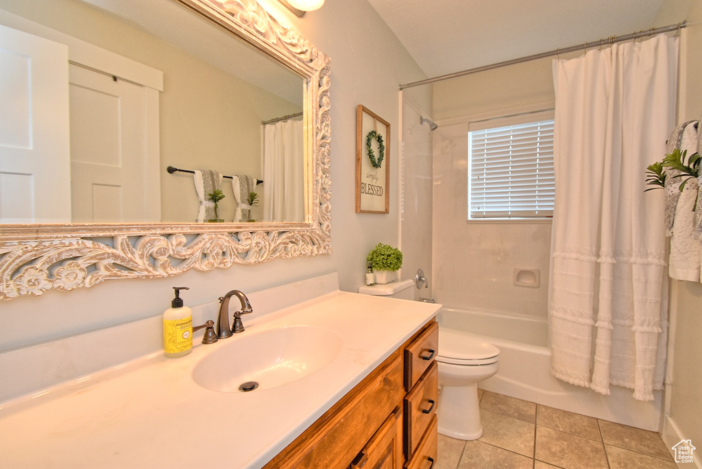 Full bathroom featuring tile floors, shower / bath combination with curtain, vanity with extensive cabinet space, and toilet