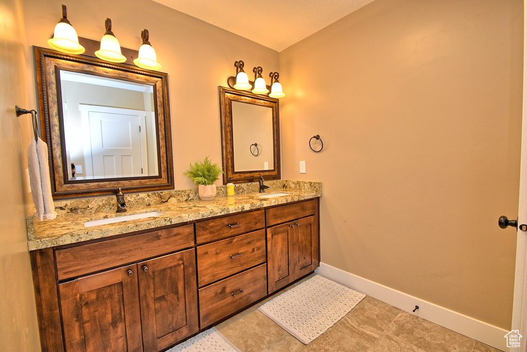Bathroom with tile flooring, vanity with extensive cabinet space, and double sink