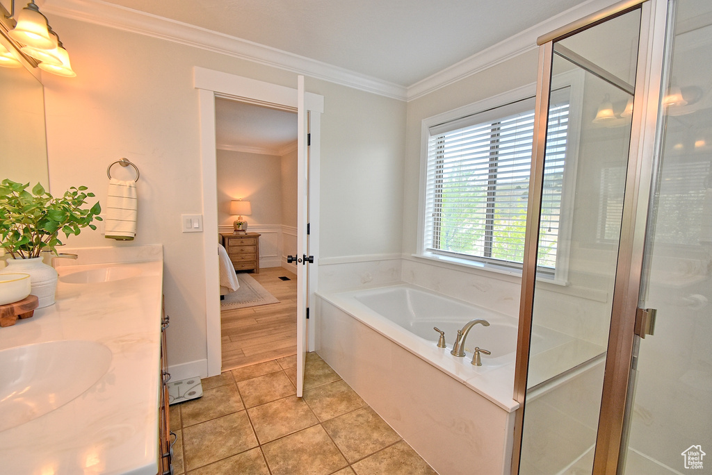 Bathroom with ornamental molding, tile flooring, shower with separate bathtub, and dual vanity