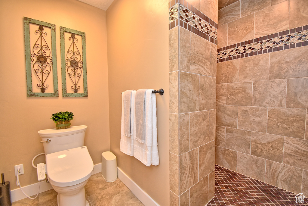 Bathroom with toilet, tile flooring, and a tile shower