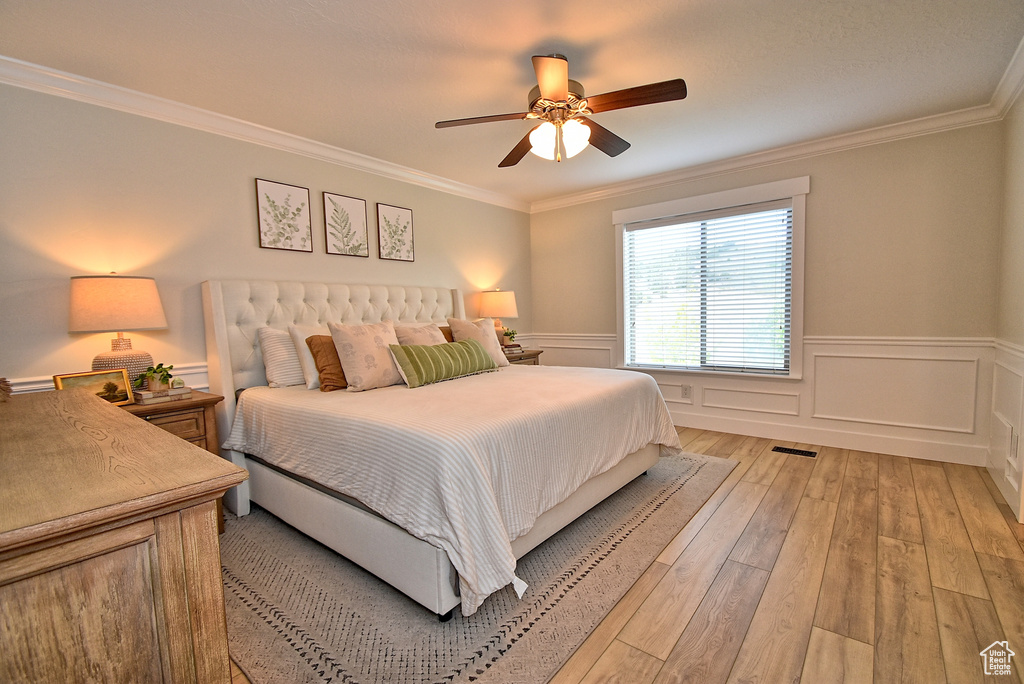 Bedroom with crown molding, light hardwood / wood-style floors, and ceiling fan