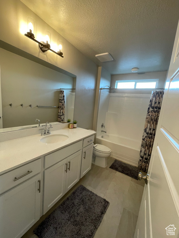 Full bathroom featuring oversized vanity, shower / tub combo, toilet, a textured ceiling, and tile floors