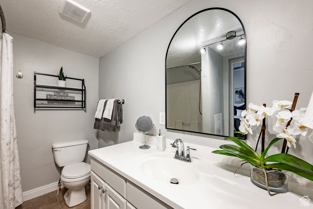 Bathroom featuring toilet, tile floors, vanity, and a textured ceiling