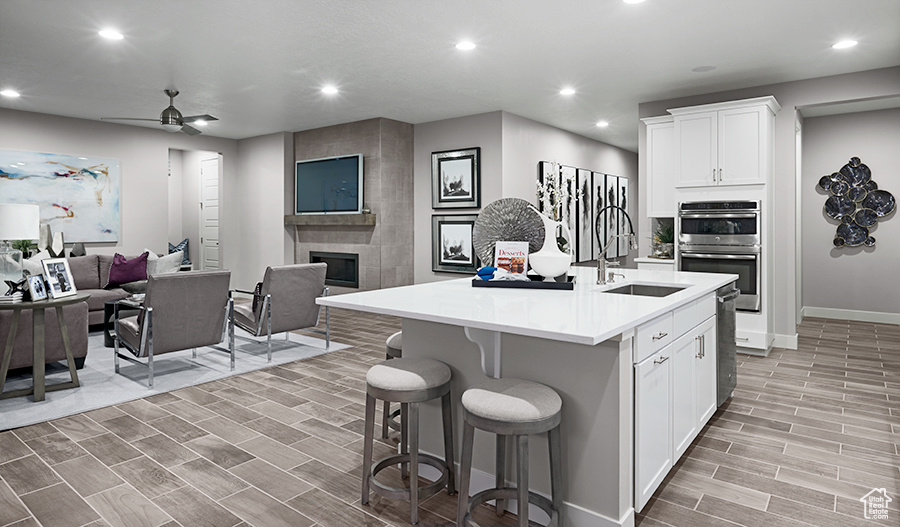Kitchen with ceiling fan, stainless steel appliances, a tile fireplace, a kitchen island with sink, and sink