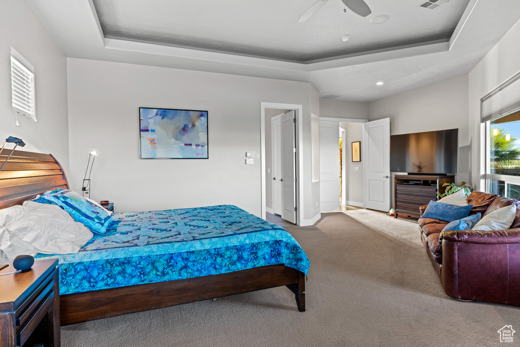 Bedroom featuring ceiling fan, carpet floors, and a tray ceiling