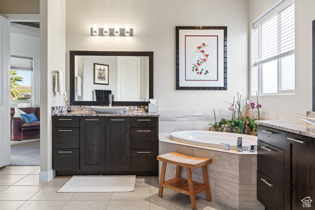 Bathroom featuring plenty of natural light, double sink vanity, tile floors, and a bath