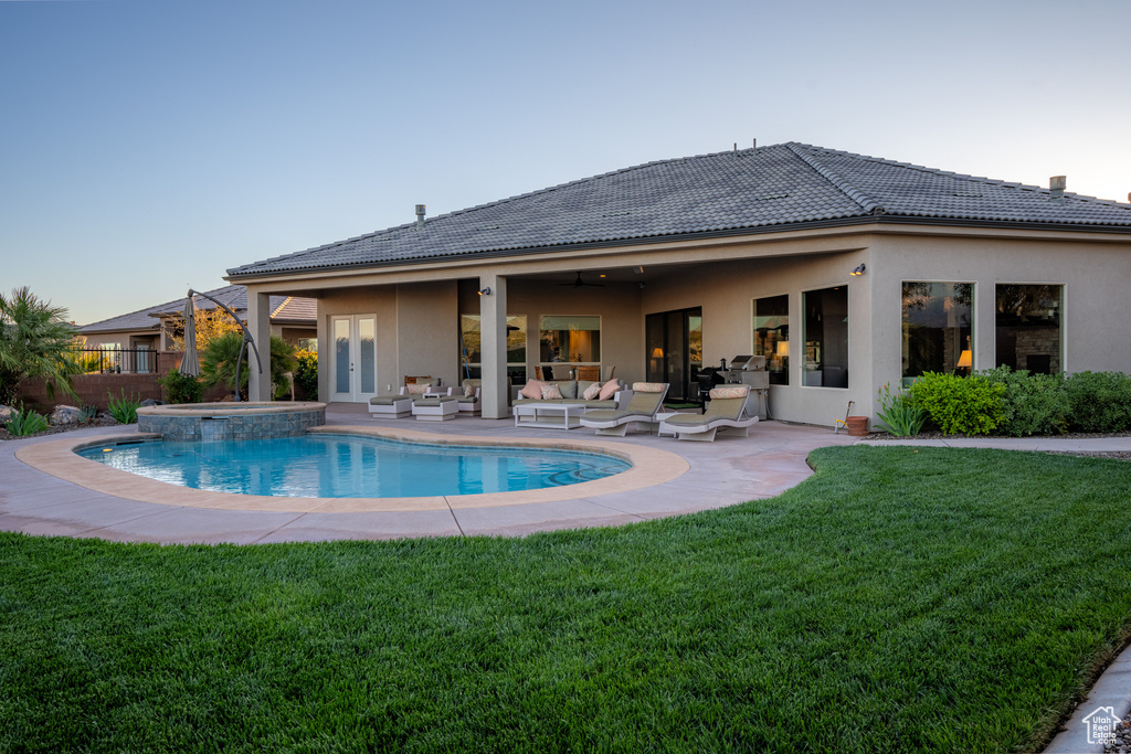 View of swimming pool with a patio area, ceiling fan, an in ground hot tub, an outdoor hangout area, and a lawn