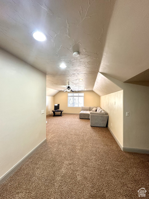 Additional living space with ceiling fan, vaulted ceiling, a textured ceiling, and carpet flooring