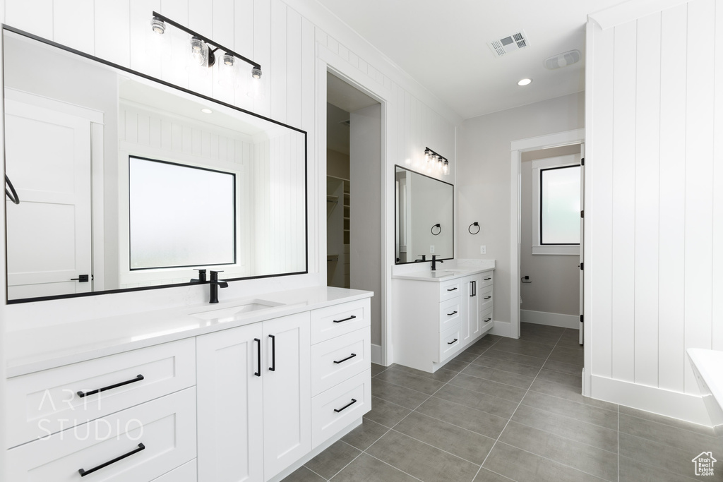 Bathroom with dual bowl vanity, a bathtub, and tile flooring