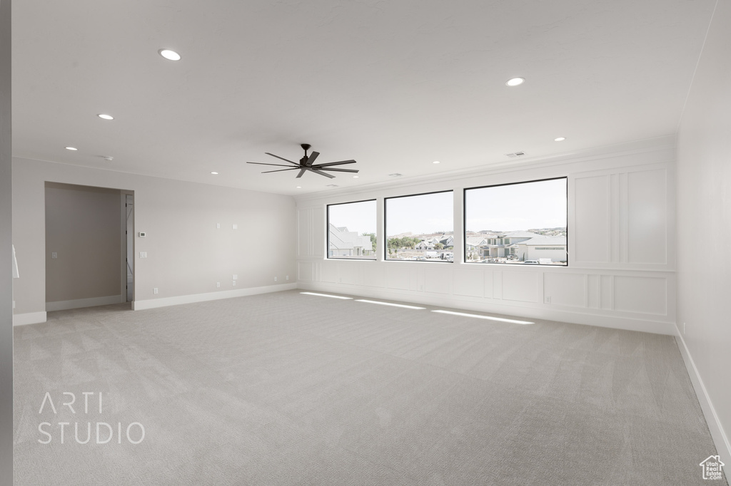 Empty room featuring crown molding, light colored carpet, and ceiling fan