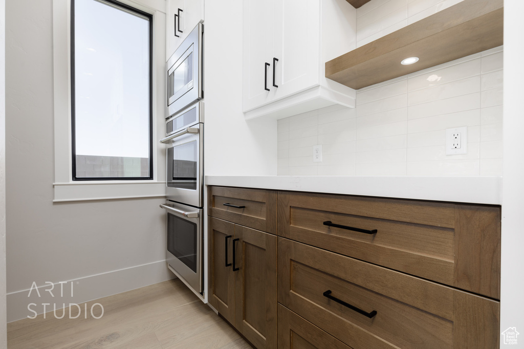Kitchen with light hardwood / wood-style flooring, tasteful backsplash, and stainless steel appliances