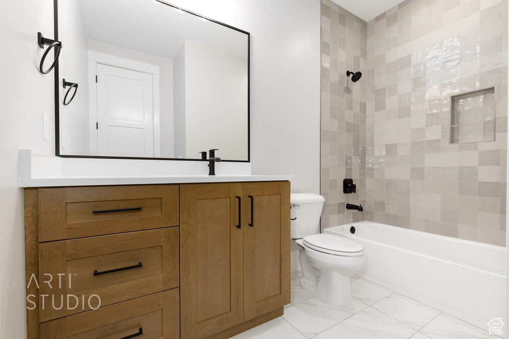 Full bathroom featuring tiled shower / bath combo, tile floors, vanity, and toilet