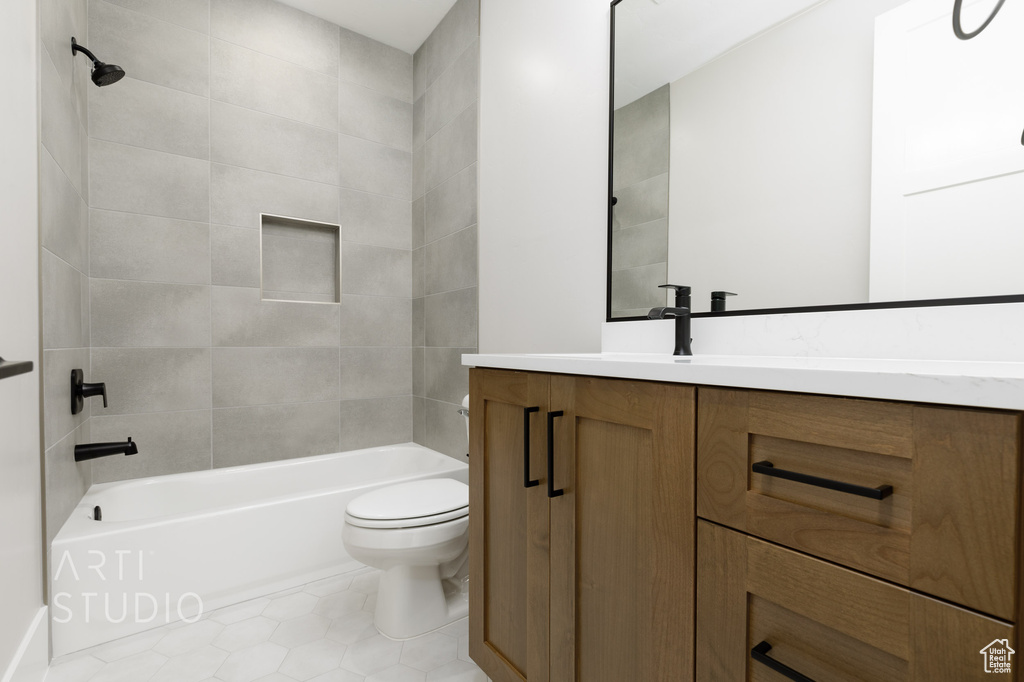 Full bathroom with tiled shower / bath combo, tile flooring, vanity, and toilet