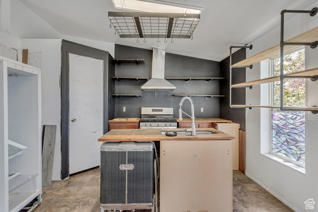 Kitchen with a center island with sink, island exhaust hood, tile floors, and stainless steel range oven