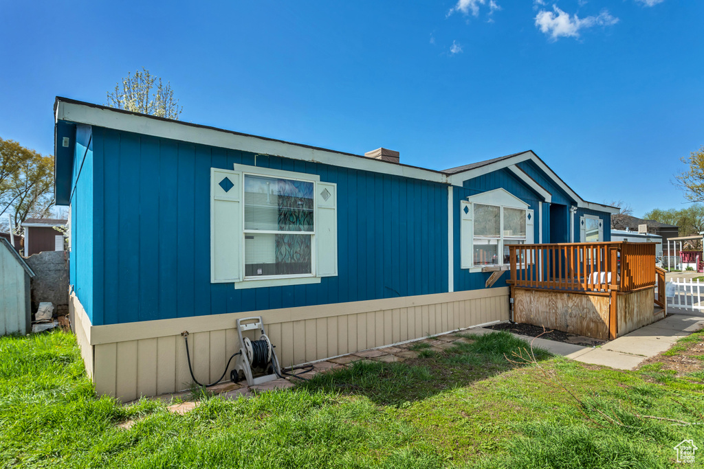 View of front of home with a deck and a front lawn