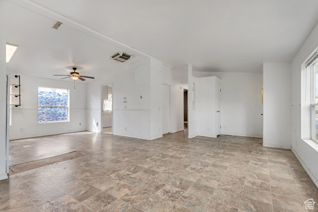 Tiled empty room featuring plenty of natural light and ceiling fan