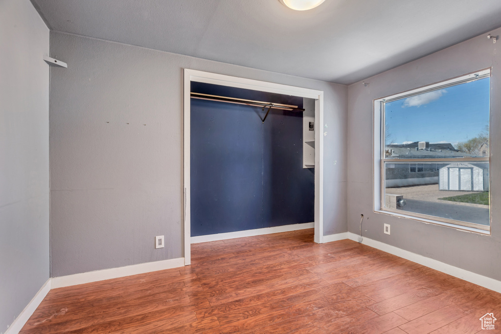 Unfurnished bedroom with a closet, hardwood / wood-style floors, and multiple windows