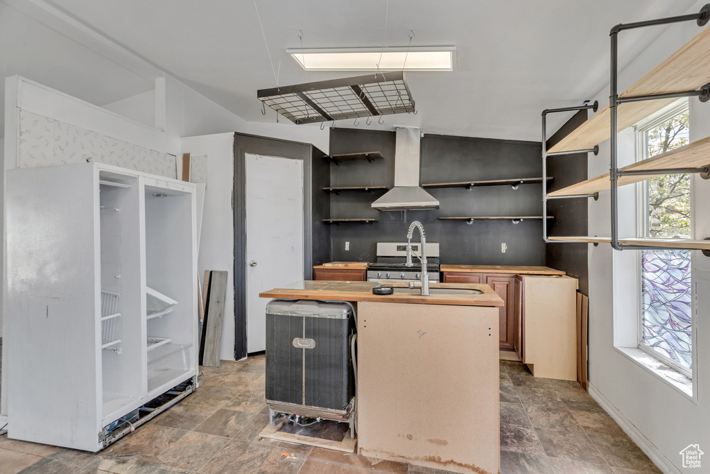 Kitchen with stainless steel stove, sink, tile floors, island exhaust hood, and a kitchen island with sink