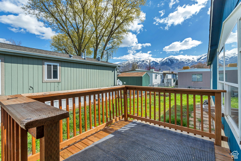 Wooden terrace featuring a mountain view, a storage shed, and a yard