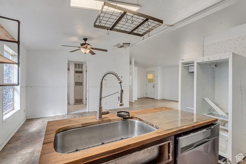 Kitchen with wood counters, light tile floors, sink, dishwasher, and ceiling fan