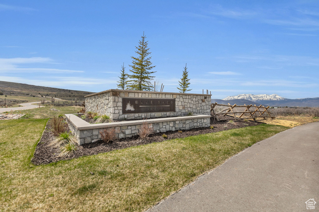 Community / neighborhood sign with a mountain view and a lawn