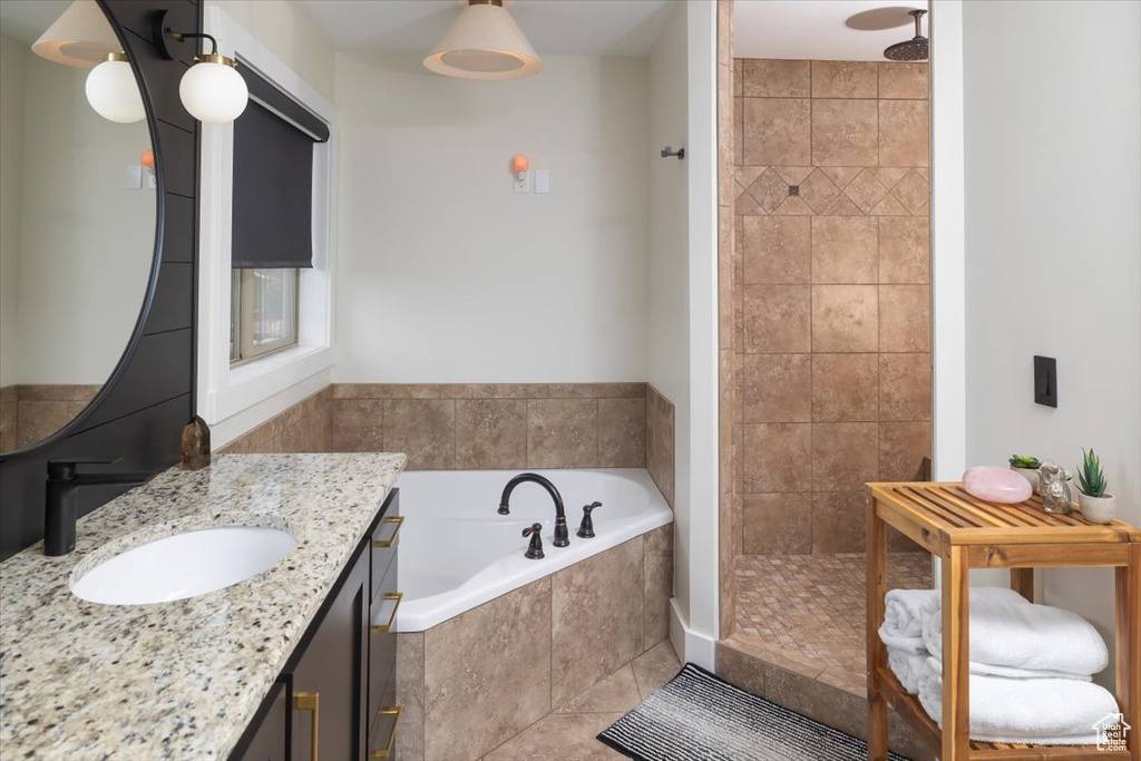 Bathroom featuring tile flooring, oversized vanity, and a relaxing tiled bath