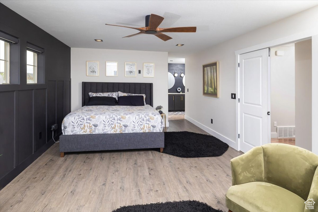 Bedroom with ensuite bath, ceiling fan, and hardwood / wood-style flooring
