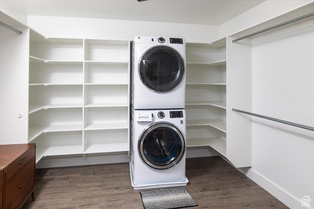 Laundry area with dark hardwood / wood-style flooring and stacked washer and dryer