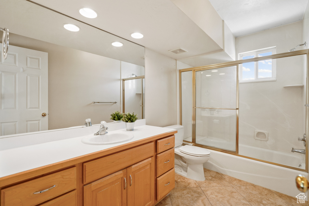 Full bathroom featuring toilet, bath / shower combo with glass door, vanity, and tile flooring