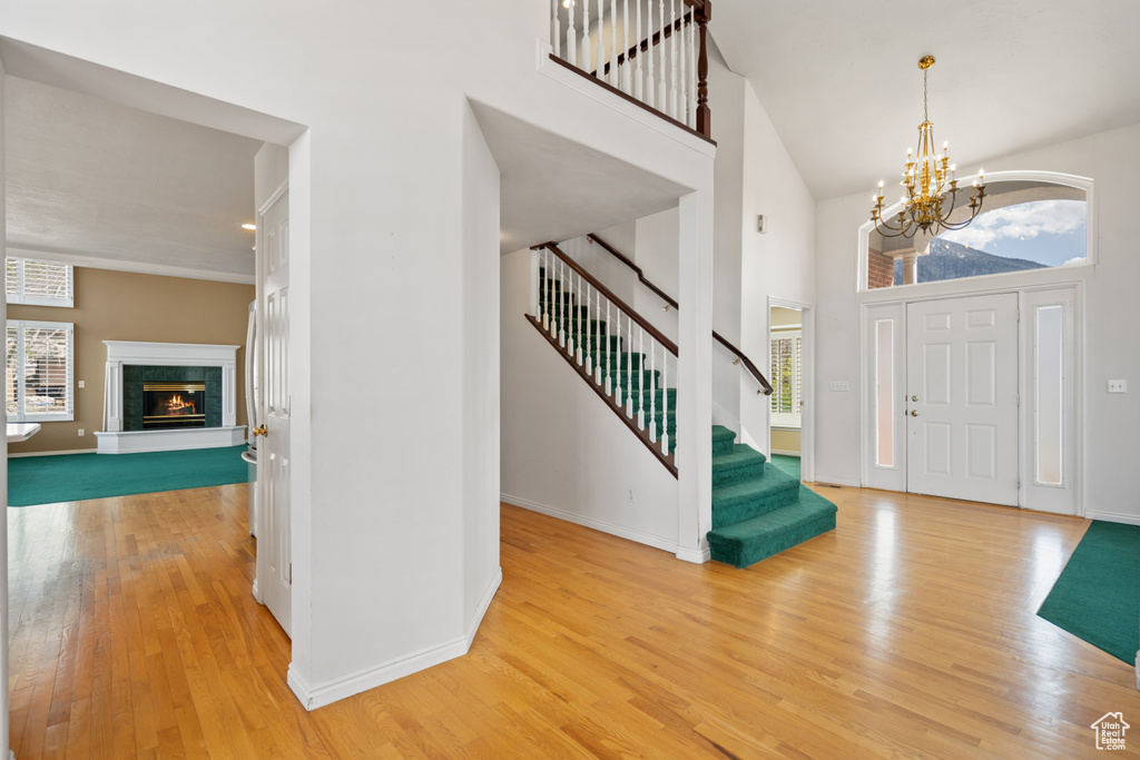 Foyer featuring light hardwood / wood-style flooring, a high ceiling, a fireplace, and an inviting chandelier