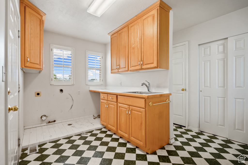 Interior space featuring tile flooring, cabinets, sink, electric dryer hookup, and gas dryer hookup