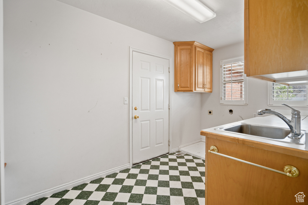 Clothes washing area with sink, hookup for an electric dryer, cabinets, and light tile floors