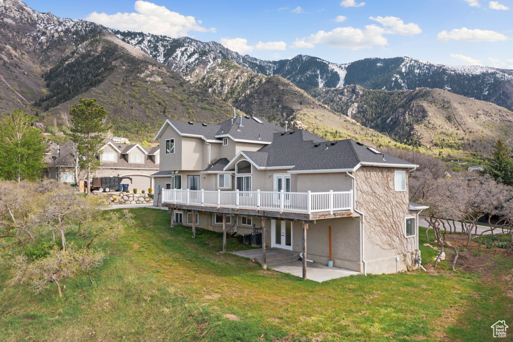 Rear view of property featuring a patio, a yard, and a mountain view