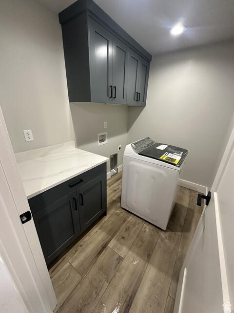 Laundry room featuring light hardwood / wood-style flooring, cabinets, and washer / dryer