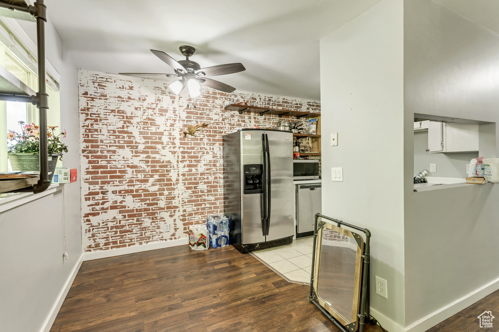 Kitchen with ceiling fan, light hardwood / wood-style flooring, stainless steel appliances, and brick wall