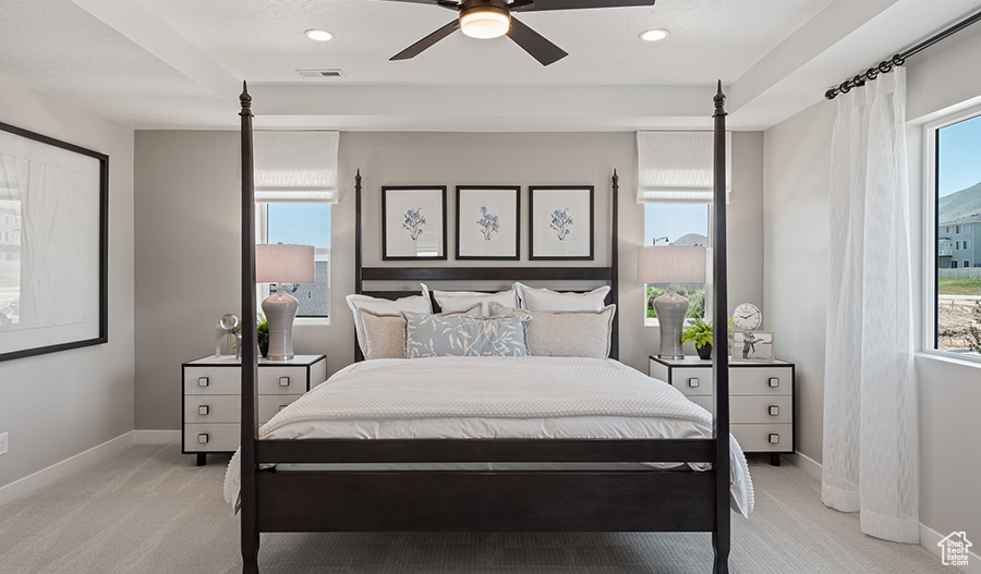 Bedroom featuring ceiling fan, light carpet, and multiple windows