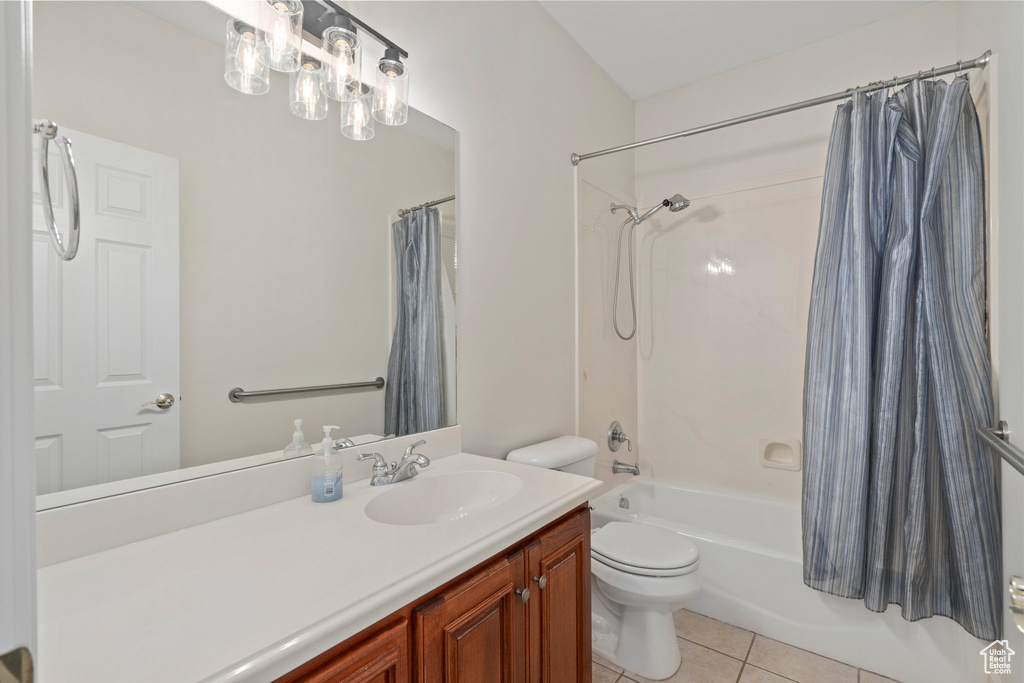 Full bathroom featuring tile floors, vanity with extensive cabinet space, toilet, and shower / tub combo with curtain