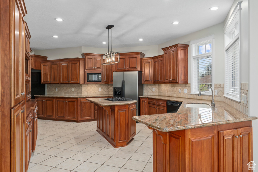 Kitchen with hanging light fixtures, a kitchen island, black appliances, tasteful backsplash, and sink