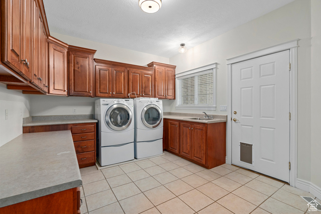 Laundry area featuring sink, cabinets, separate washer and dryer, and light tile floors