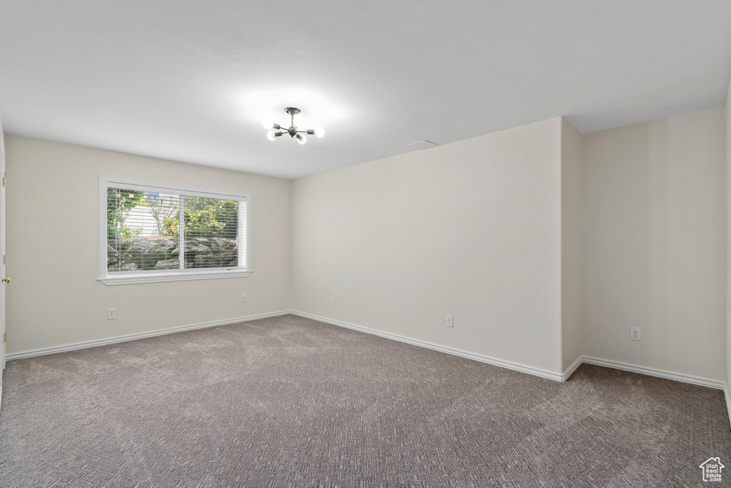 Unfurnished room with a notable chandelier and carpet