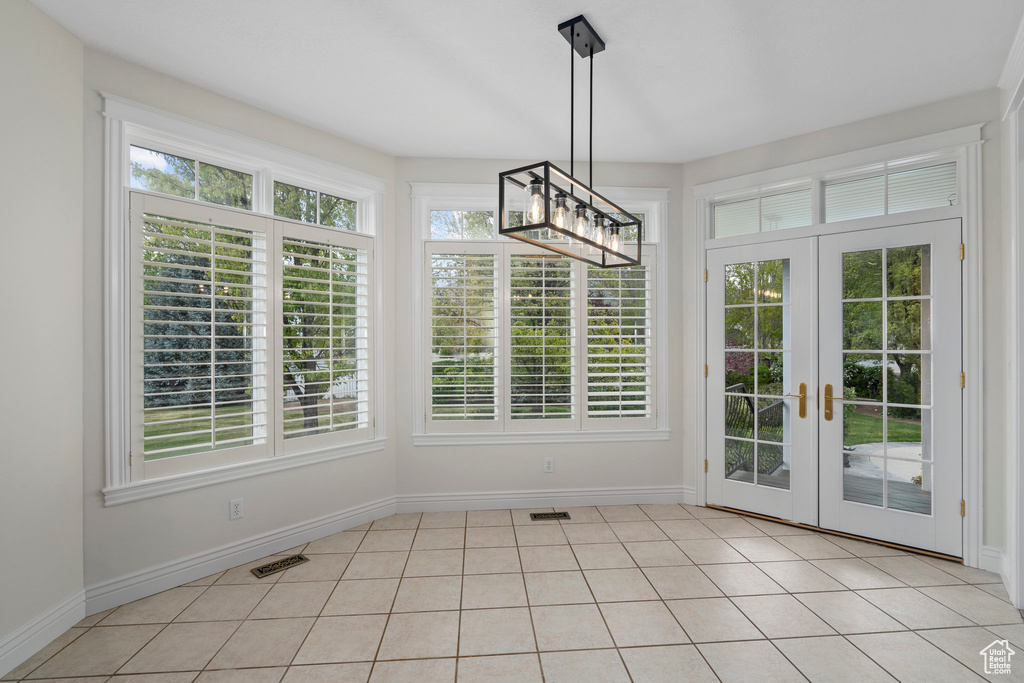 Unfurnished dining area featuring french doors, a healthy amount of sunlight, and light tile floors