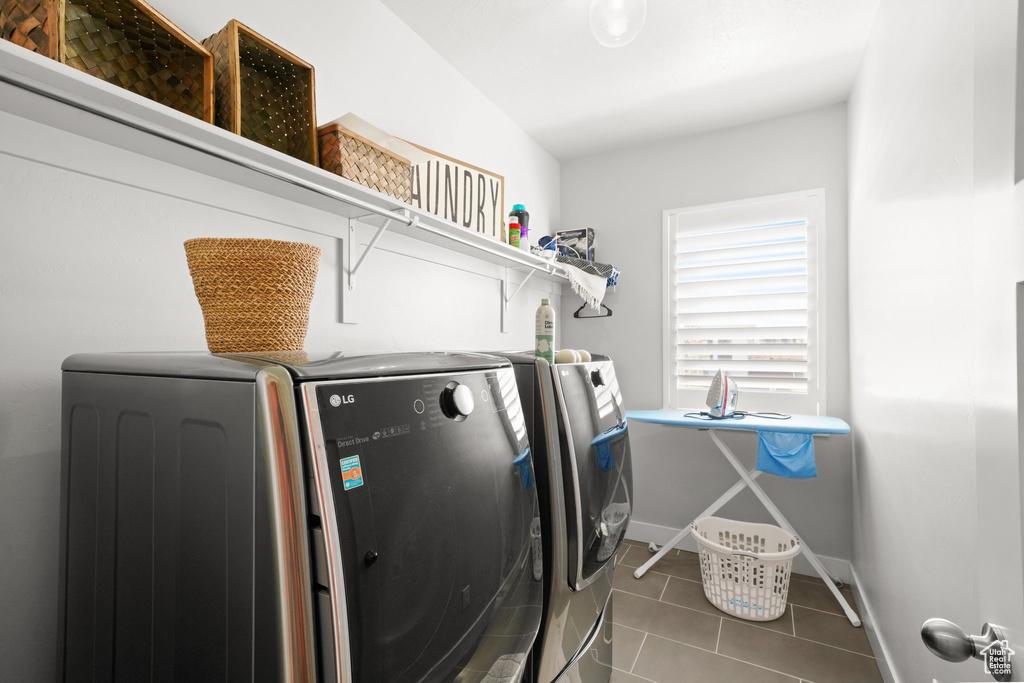 Laundry area featuring dark tile floors and washing machine and clothes dryer