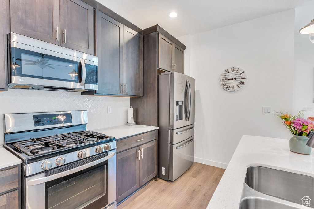 Kitchen with ceiling fan, light hardwood / wood-style floors, tasteful backsplash, dark brown cabinets, and stainless steel appliances