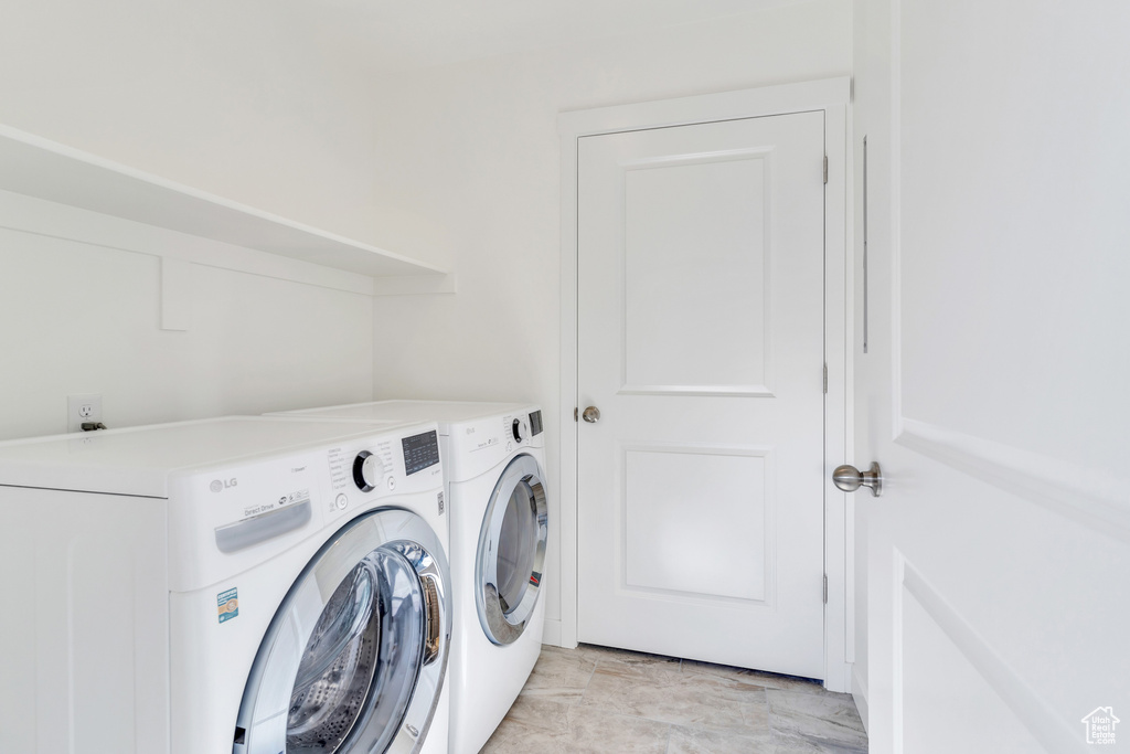Laundry area featuring light tile flooring and washer and clothes dryer