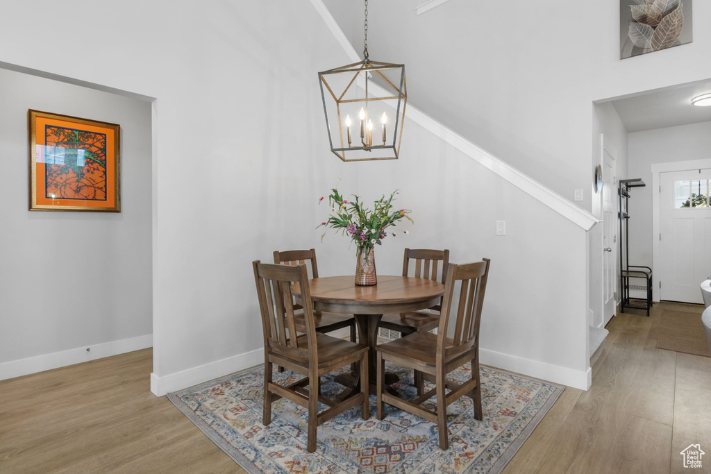Dining space featuring high vaulted ceiling, a notable chandelier, and light wood-type flooring