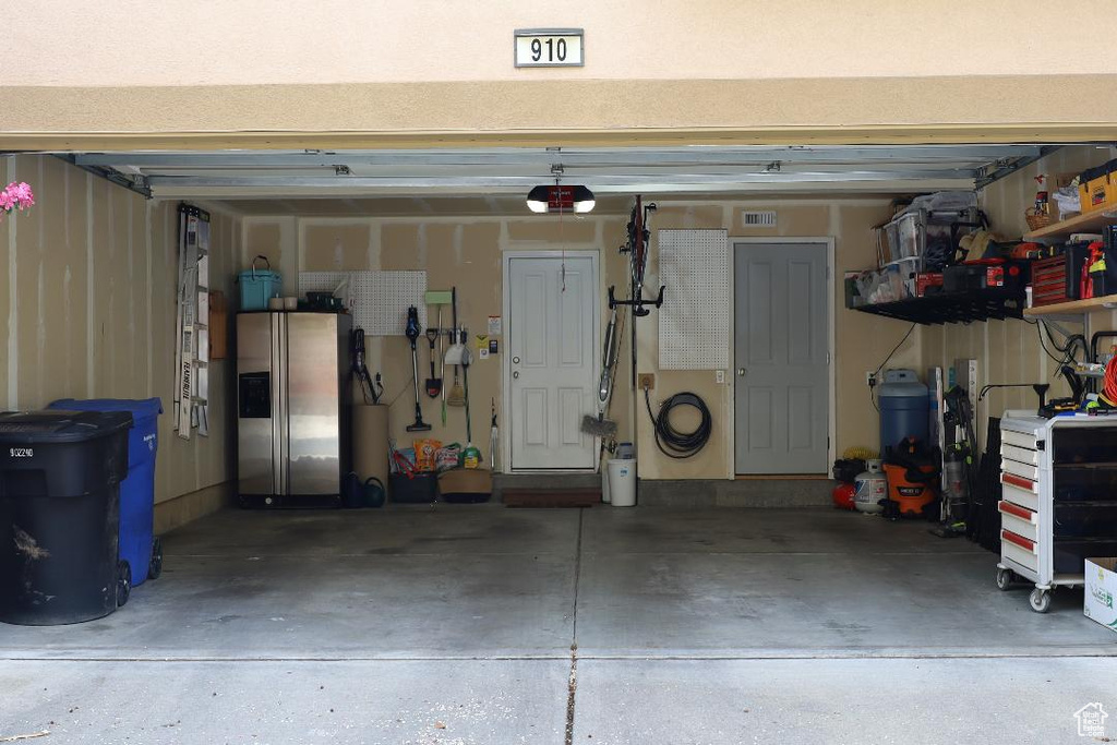 Garage with stainless steel fridge with ice dispenser and a garage door opener