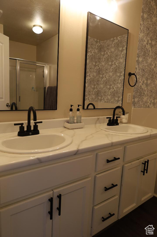 Bathroom featuring dual bowl vanity and a shower with shower door